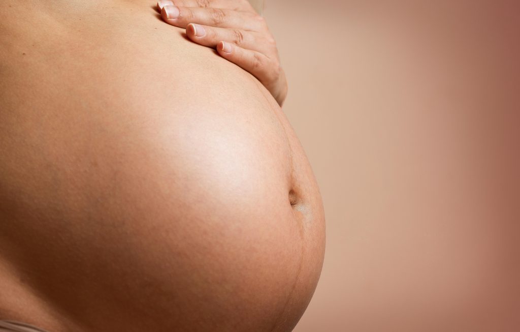 An intimate close-up of a pregnant woman's abdomen, highlighting maternity and parenthood.