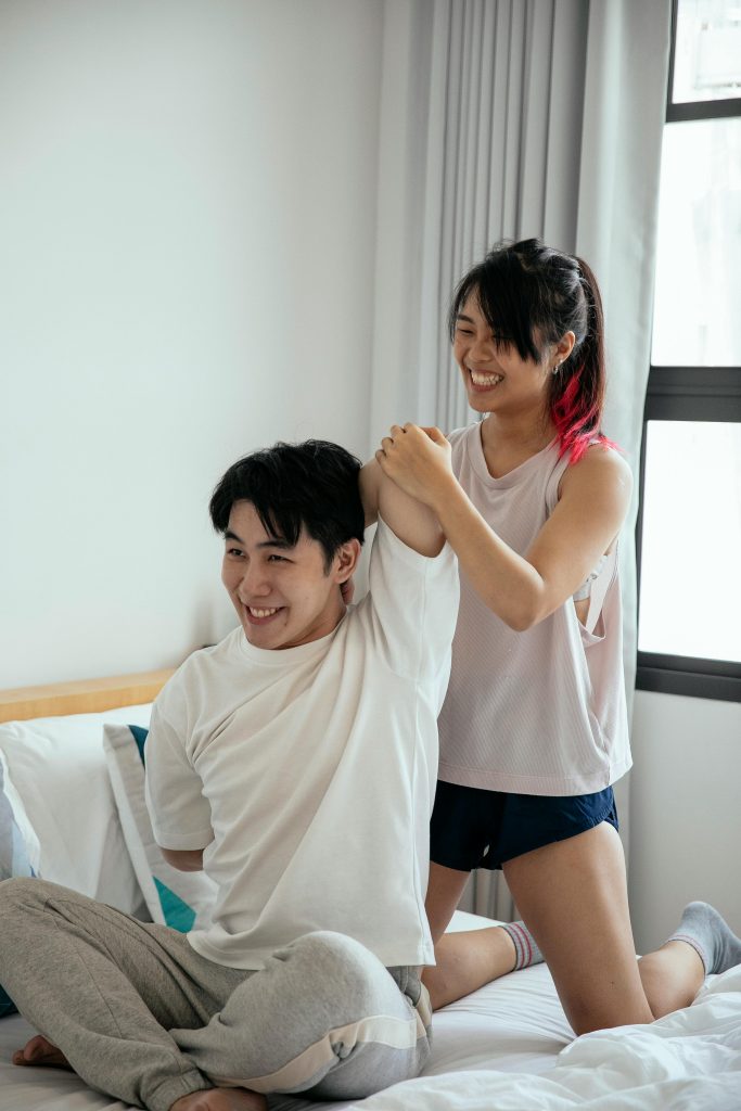 A cheerful couple stretching in a bedroom, embodying wellness and mindfulness.